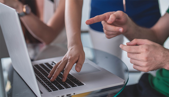 Händer som pekar och instruerar vid en datorskärm
